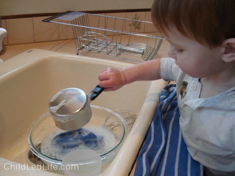 Kids learning to love washing dishes at a young age helps them with their practical life skills. Find more on a Montessori washing dishes lesson on ChildLedLife.com
